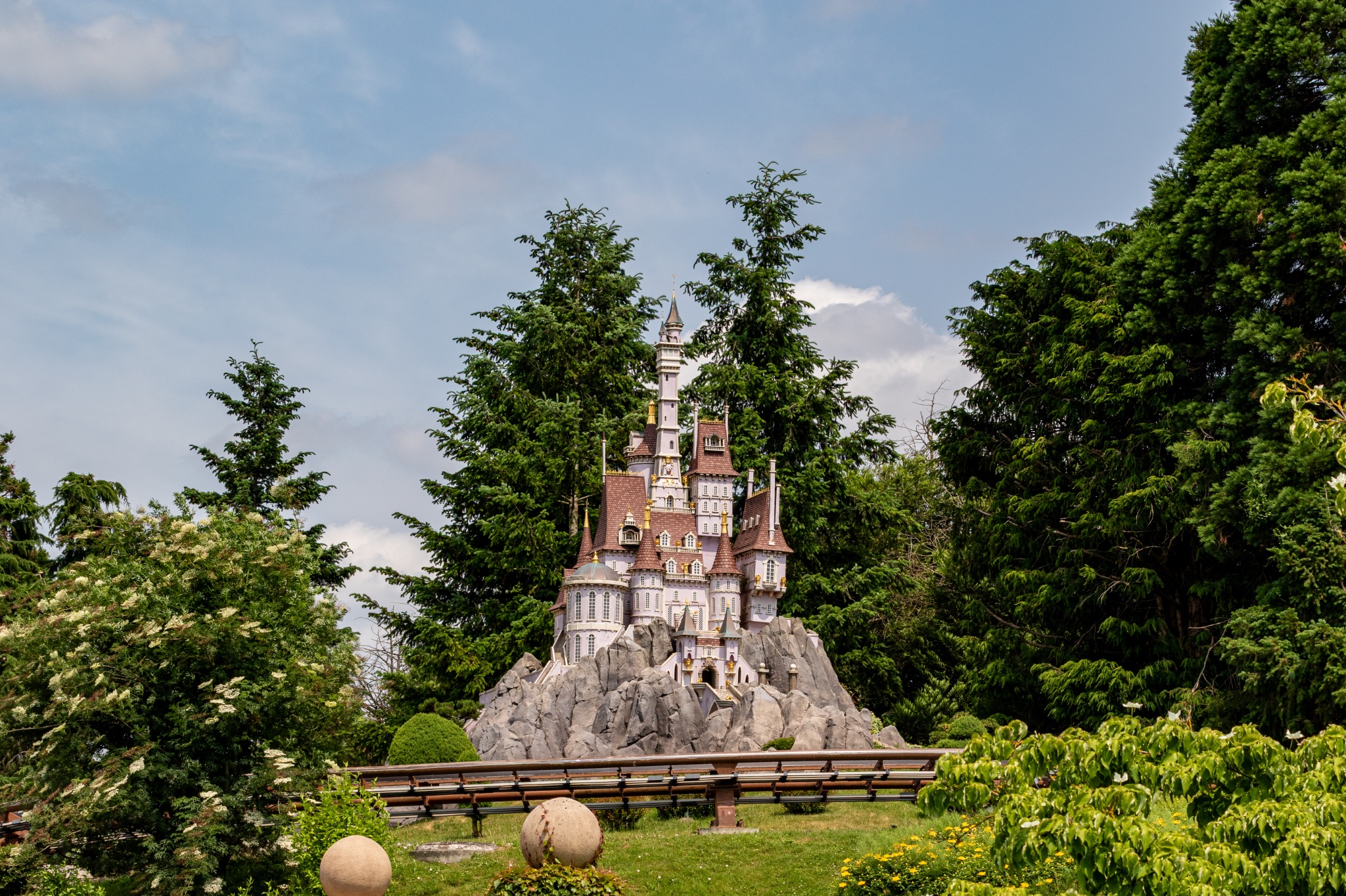 Miniature Castle Model with Train Track in Park Setting at Disneyland Paris, France.
