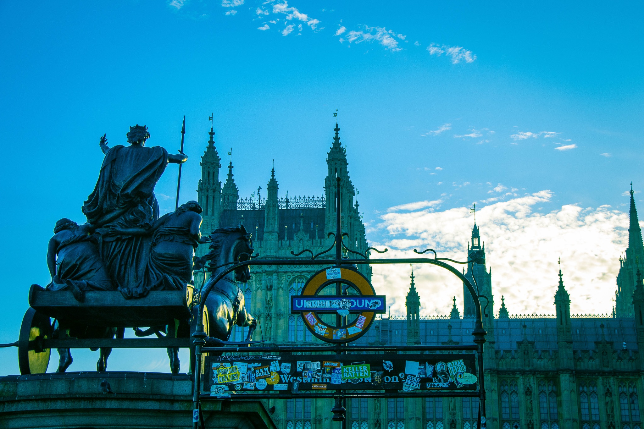 Silhouette of a statue with a Gothic cathedral in the background under a blue twilight sky.