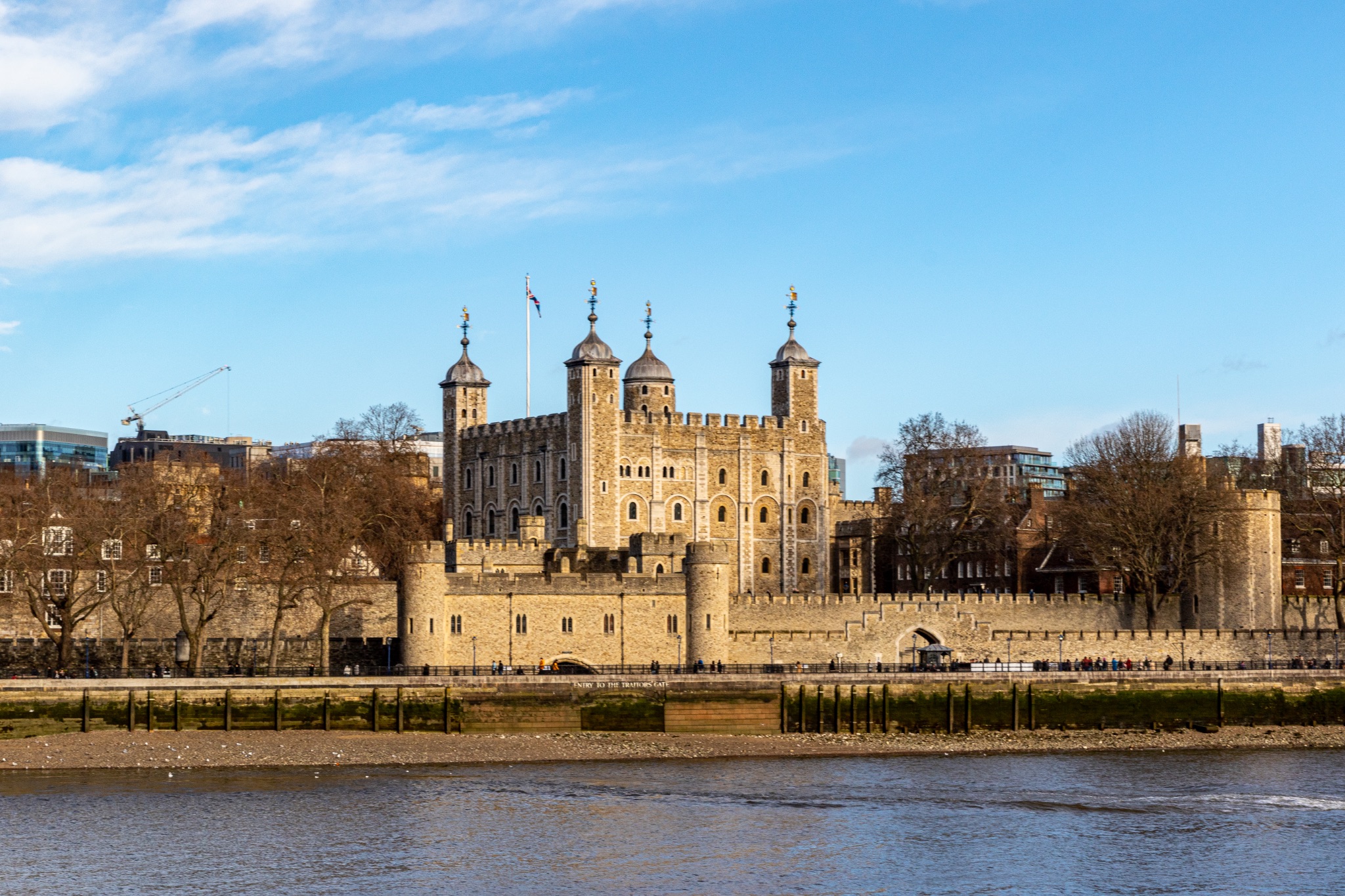 Historic Tower of London on a sunny day with clear blue skies, viewed from across the River Thames.
