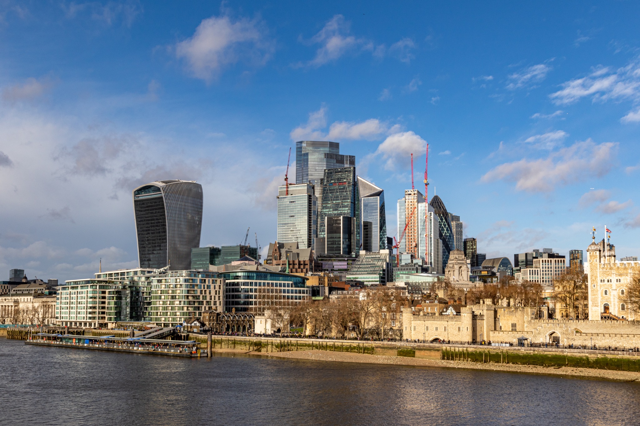 London skyline with modern buildings and blue sky, viewed from across the River Thames.