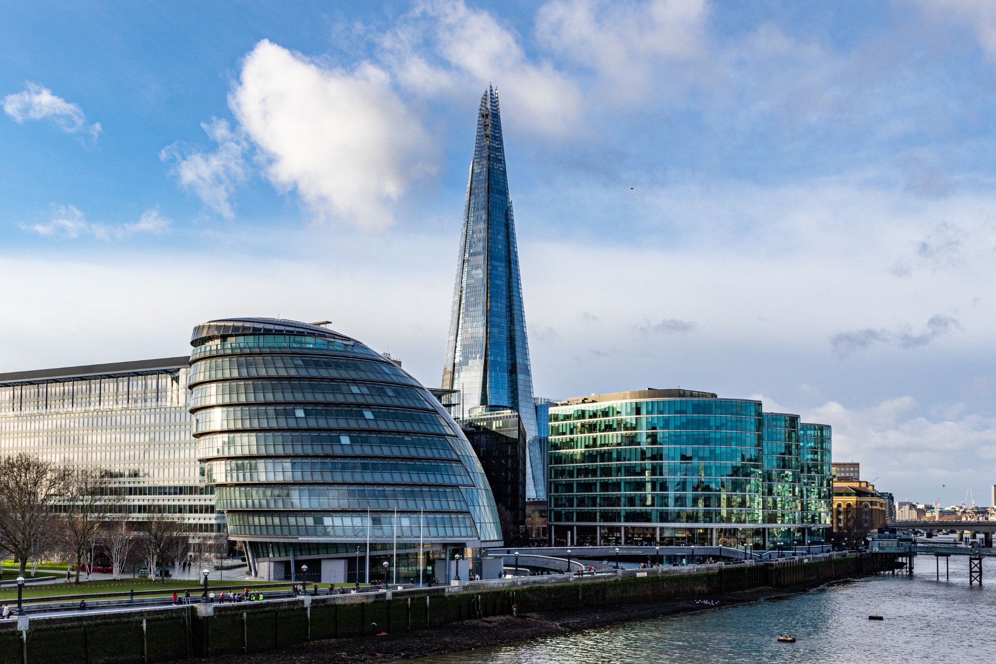 Modern London skyline with The Shard and City Hall against a cloudy sky.