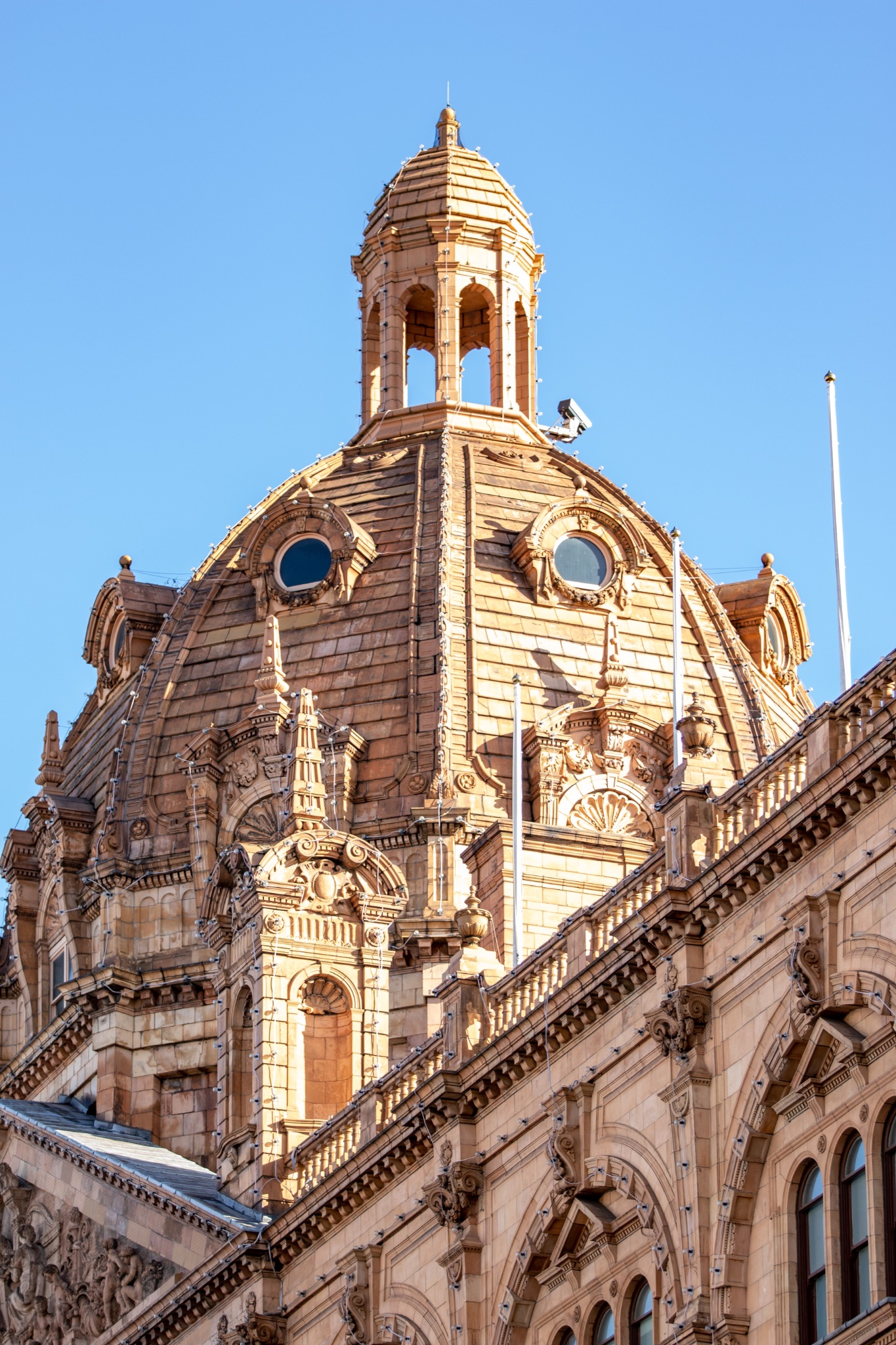 Elegant historical building facade with ornate dome and sculptures against a clear blue sky