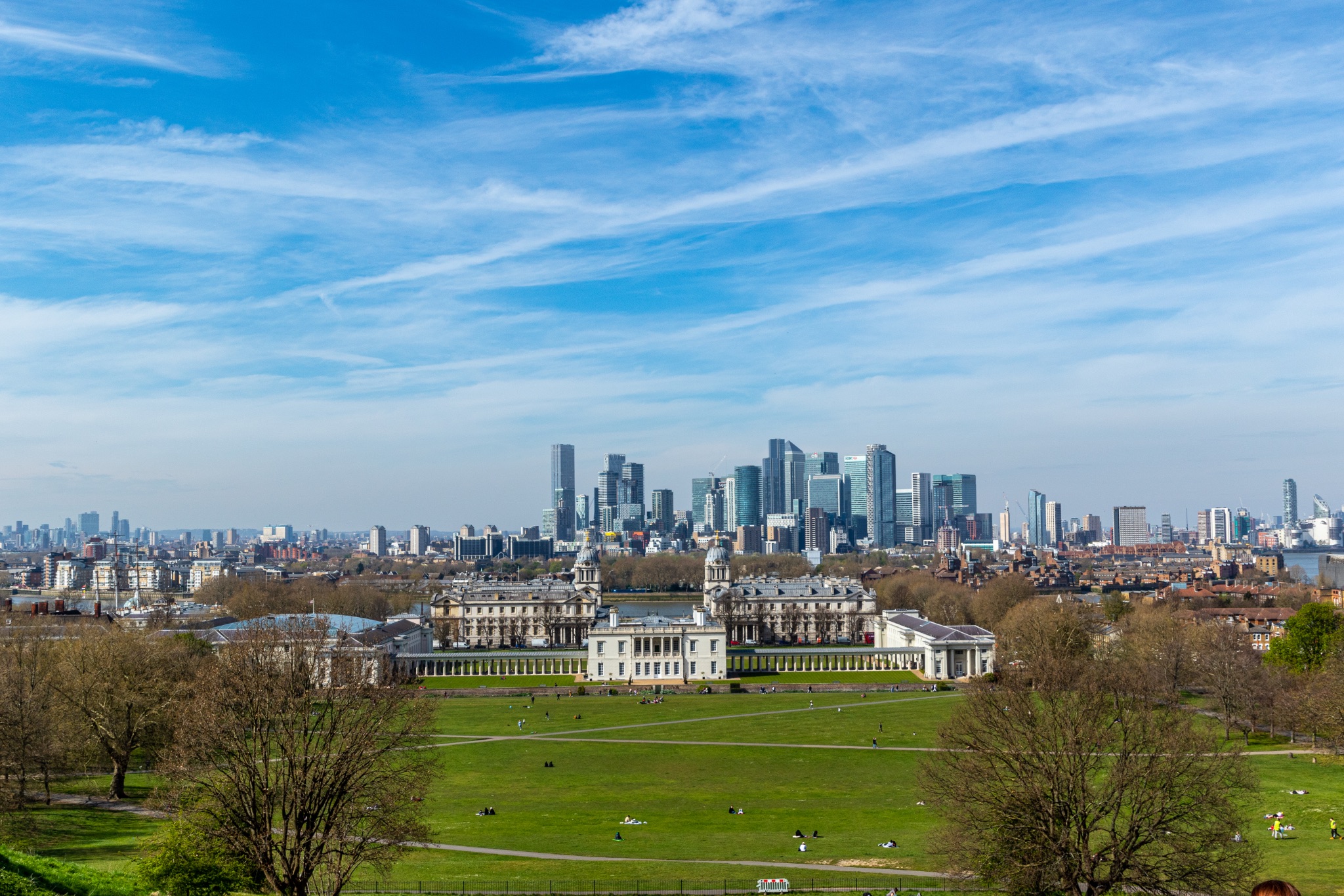 Panoramic view of a city skyline with historic buildings in the foreground and modern skyscrapers in the distance under a clear blue sky.