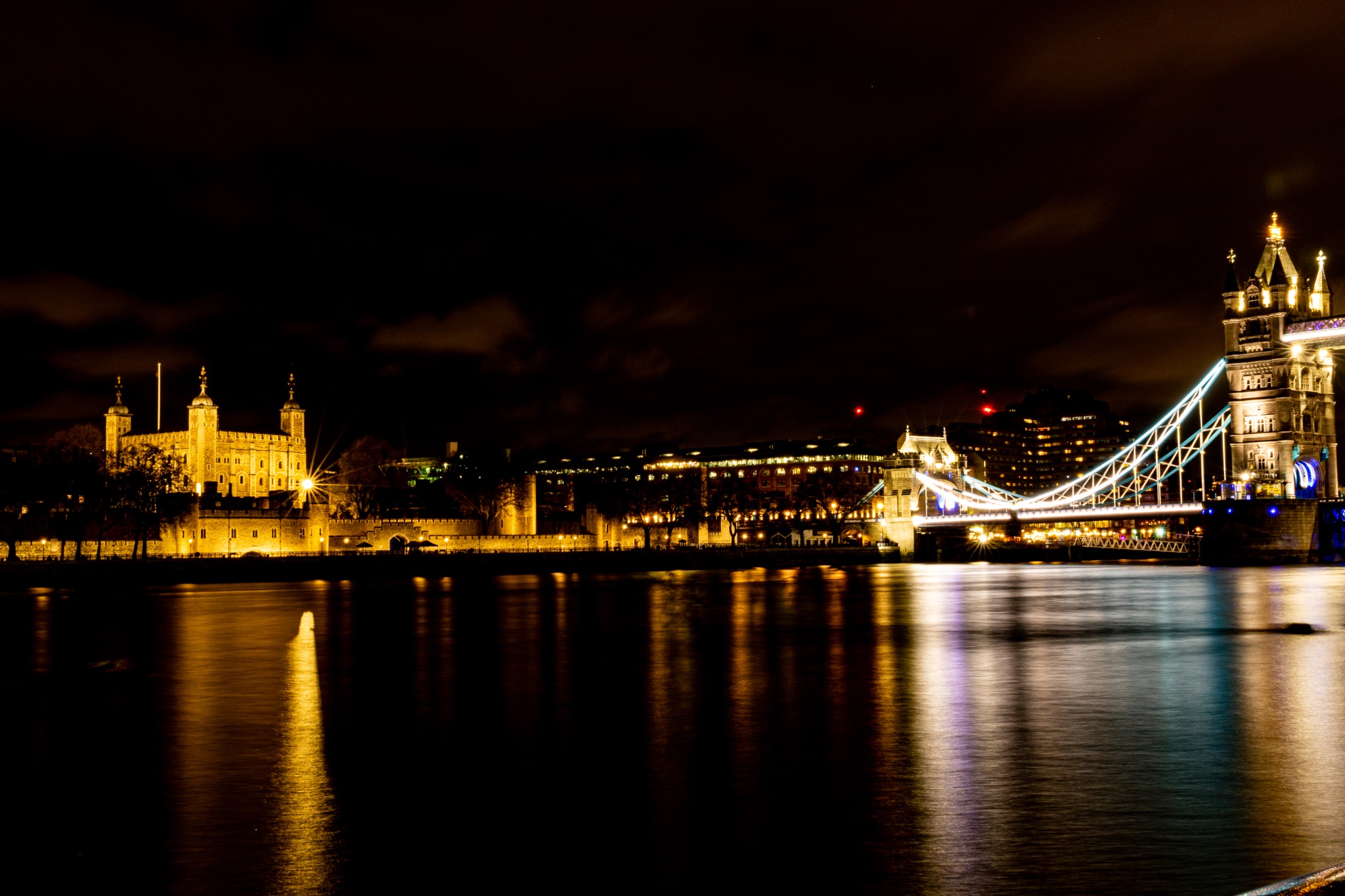 Night view of Tower Bridge in London with reflections on the Thames River.
