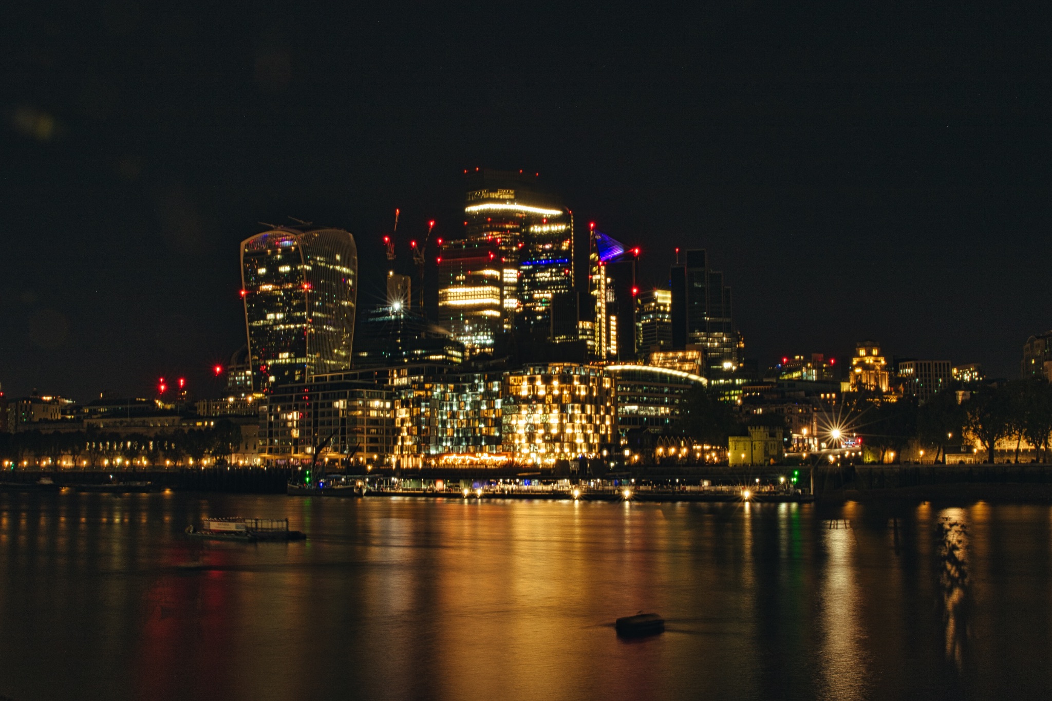 Night cityscape with illuminated buildings reflected on water surface.