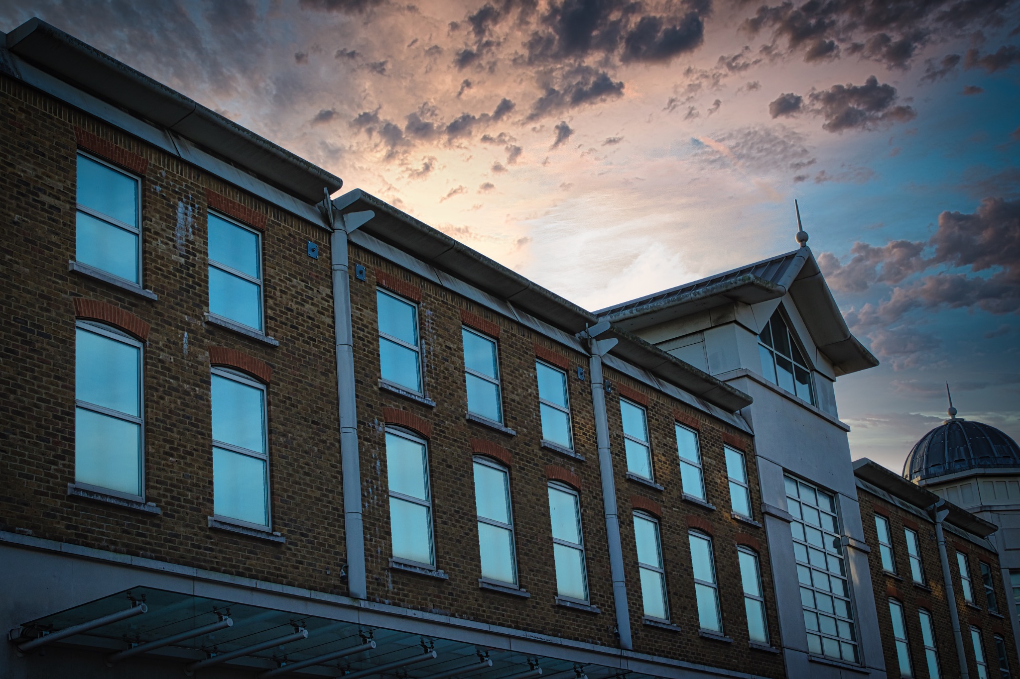 Classic building facade against a dramatic sunset sky with clouds.