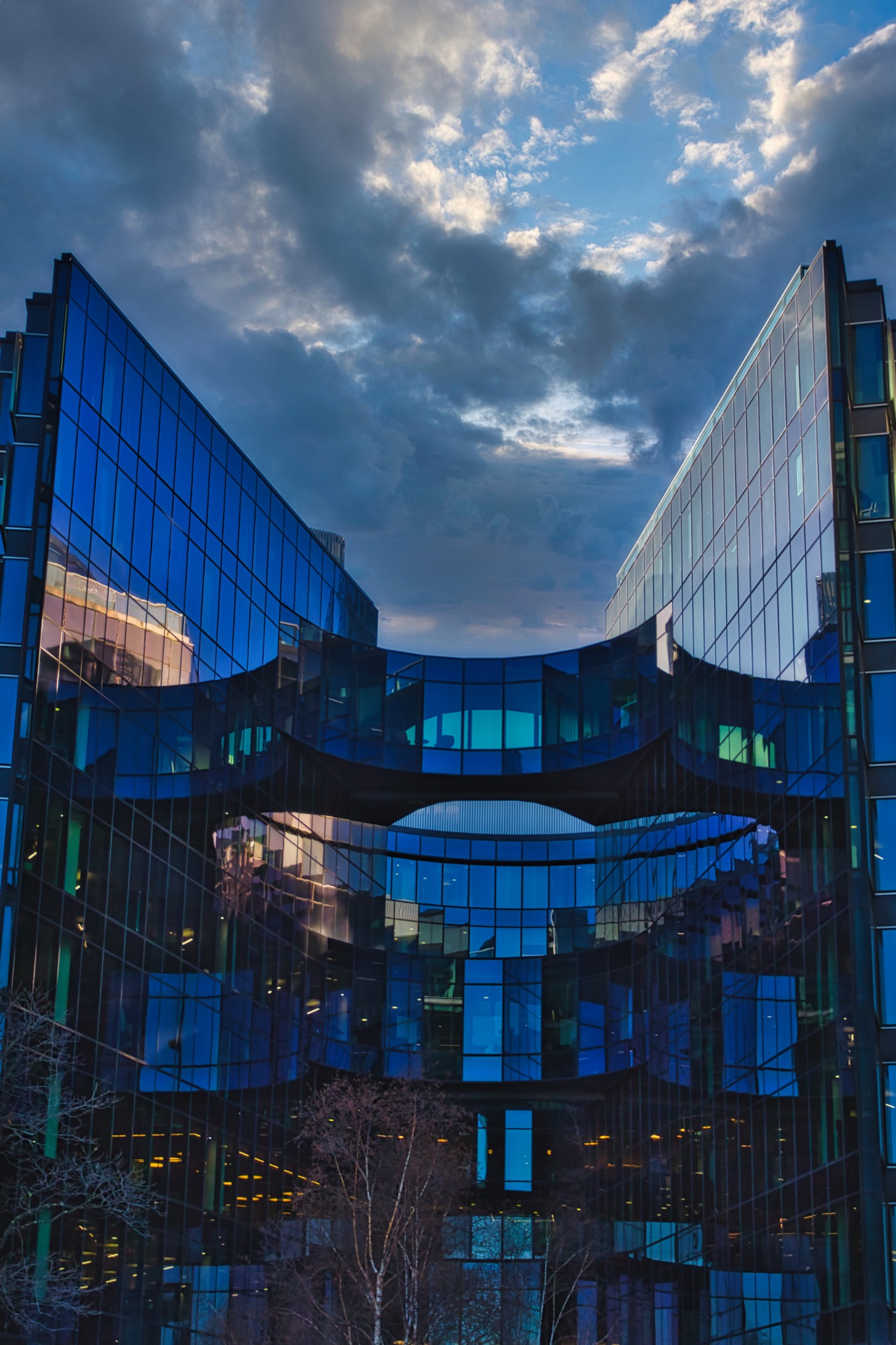 Modern Glass Building with Connecting Bridge under Cloudy Sky in London, UK.