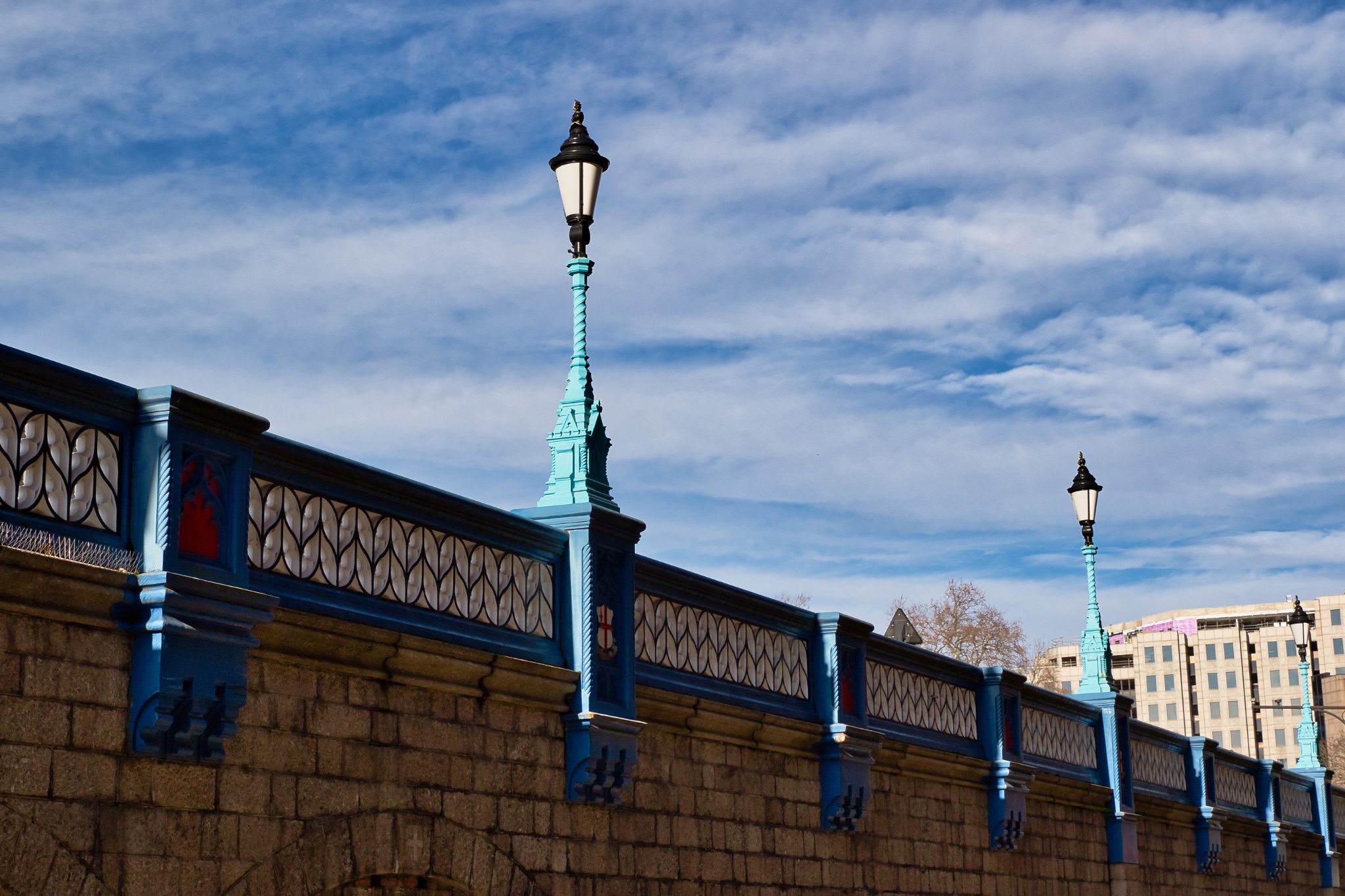 Stone Wall with Teal Railing and Ornate Lamps in London, UK.