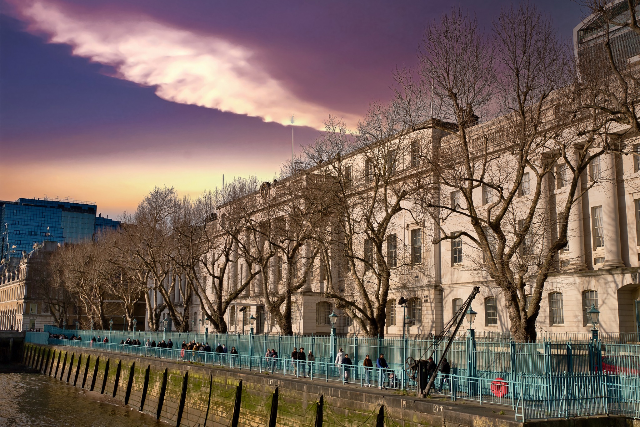 Waterfront Building with Pedestrians and Winter Trees in London, UK.