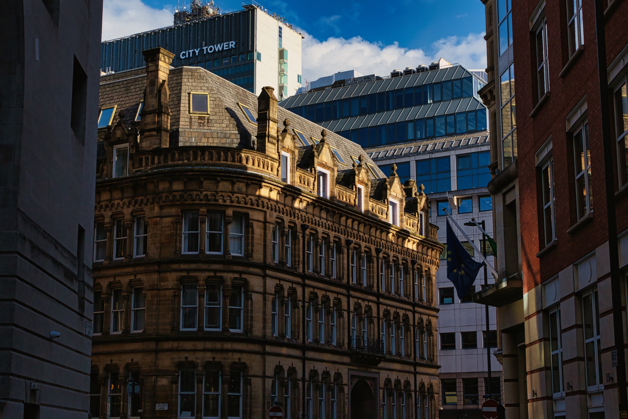 City Street with Historic Buildings and Modern Glass Structure in Manchester, UK.