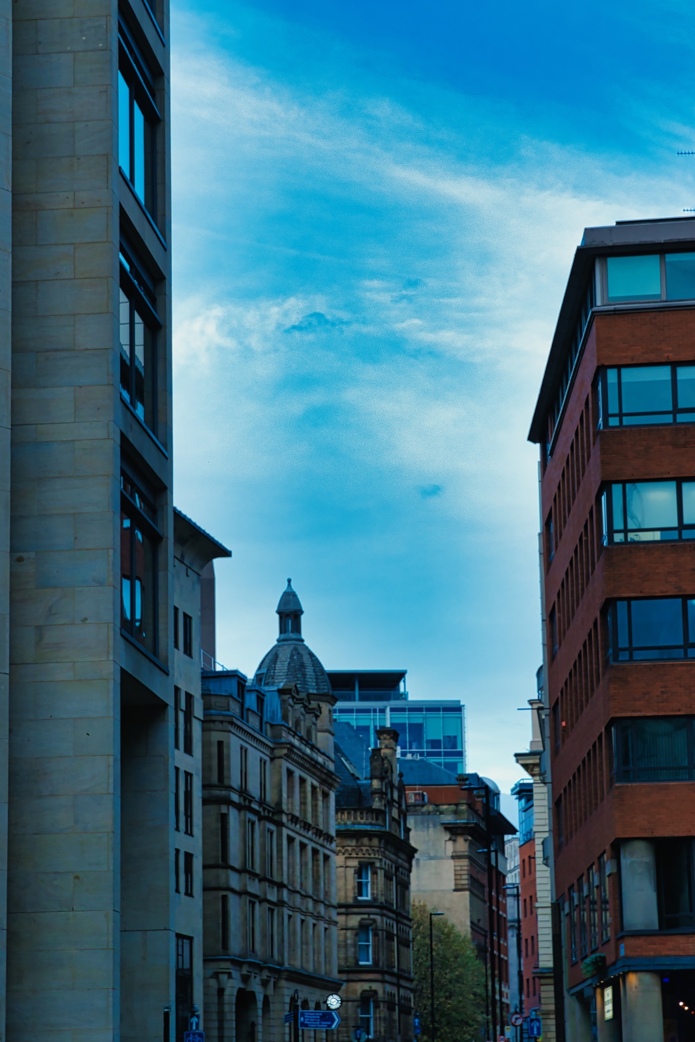 Urban landscape with modern and traditional buildings against a blue sky with clouds in Manchester, England.