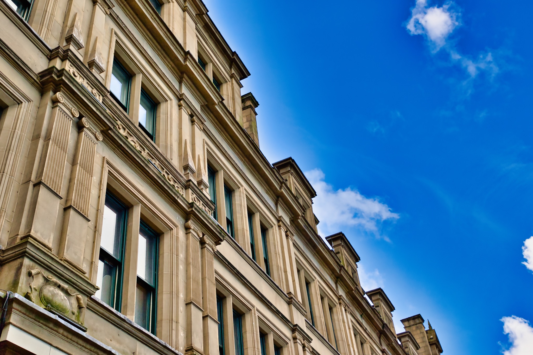Multi-Story Building Facade Against Blue Sky in Manchester, UK.