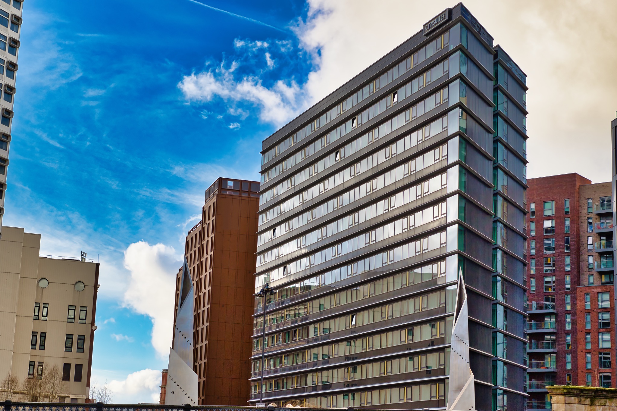 Cityscape with Multi-Story Glass Building and Adjacent Structures in Manchester, UK.