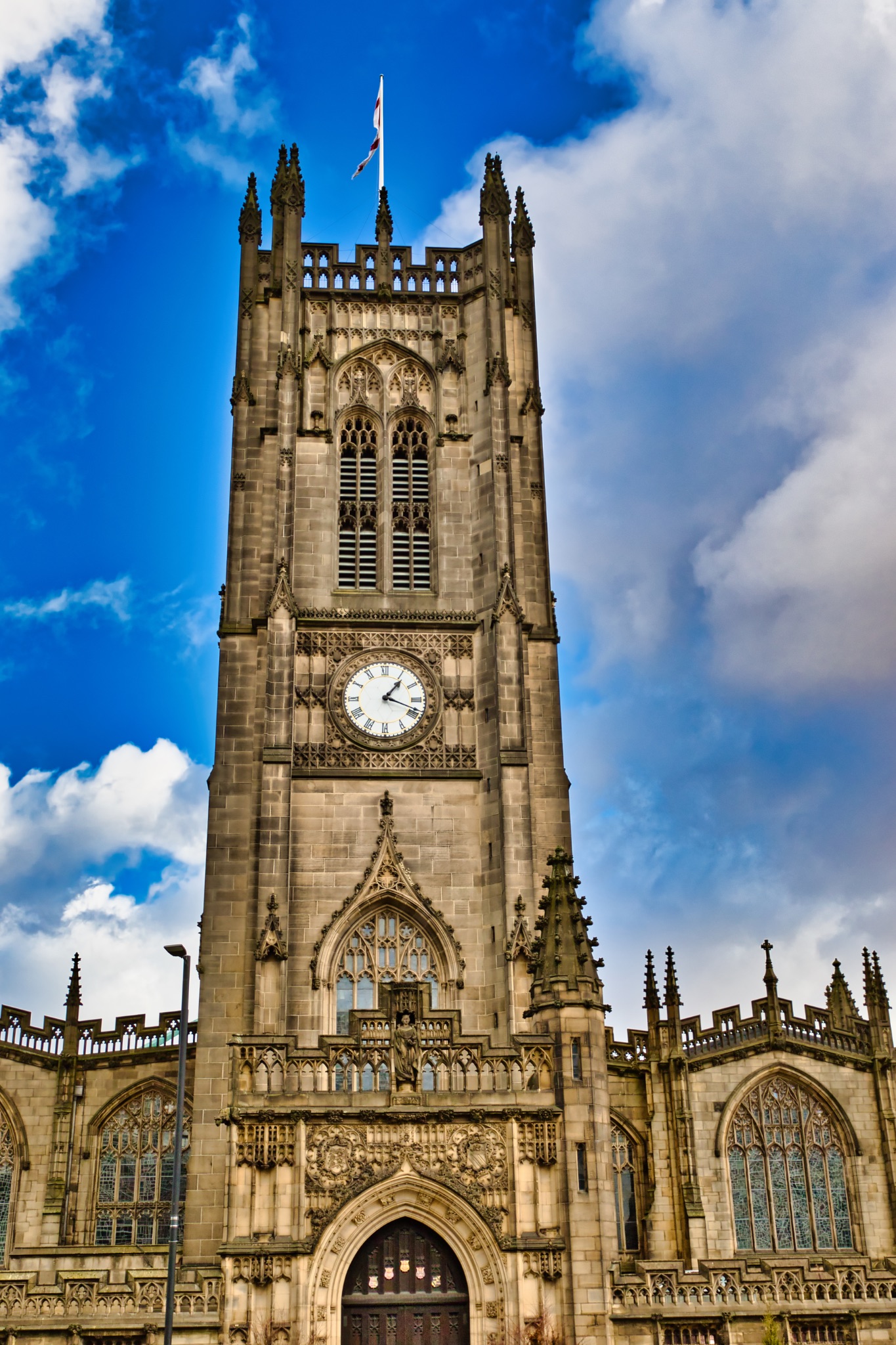 Exterior View of Church Tower with Clock and Gothic Details in Manchester, UK.