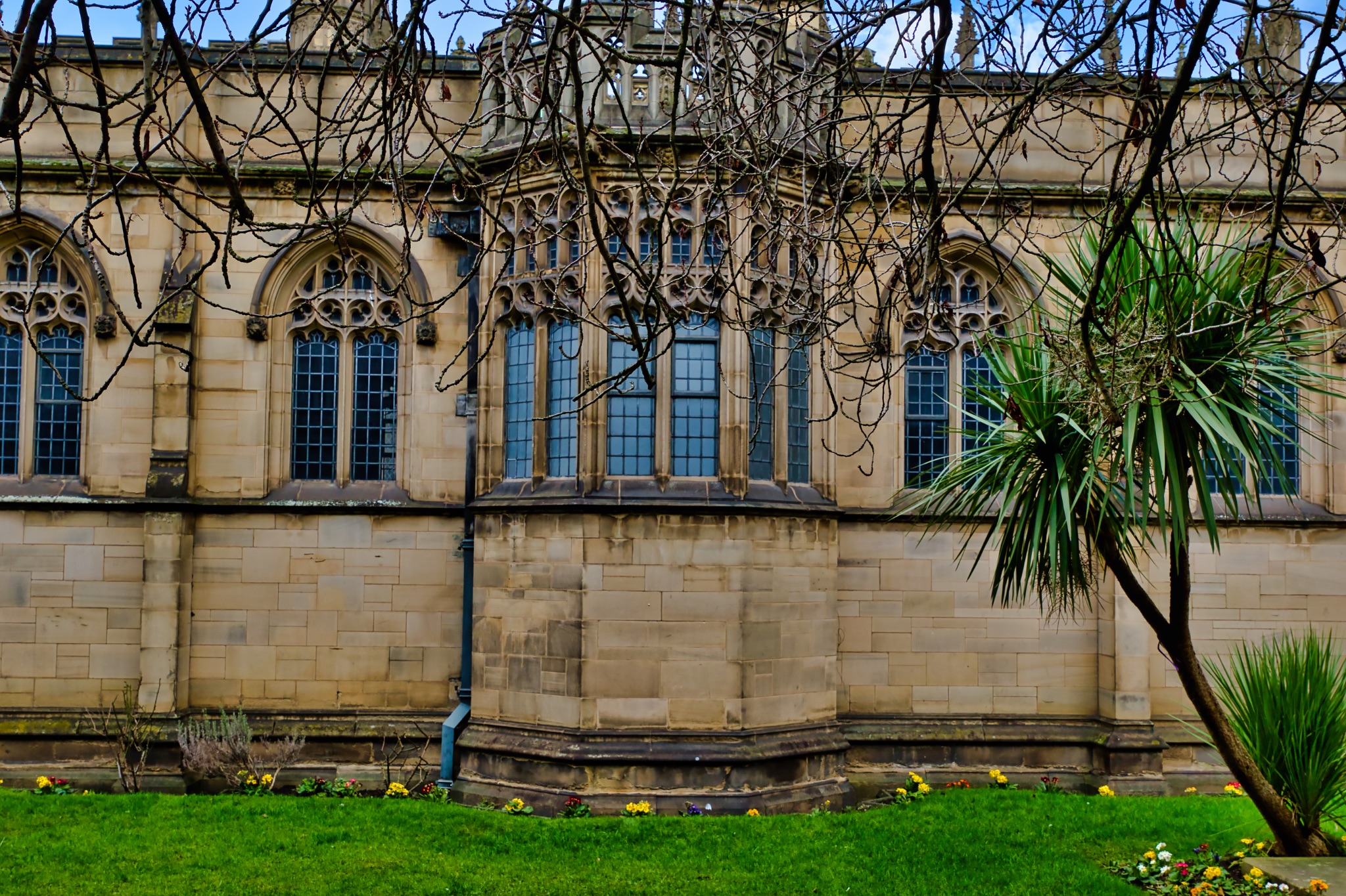 Stone Building Exterior with Gothic Windows and Landscaping in Manchester, UK.