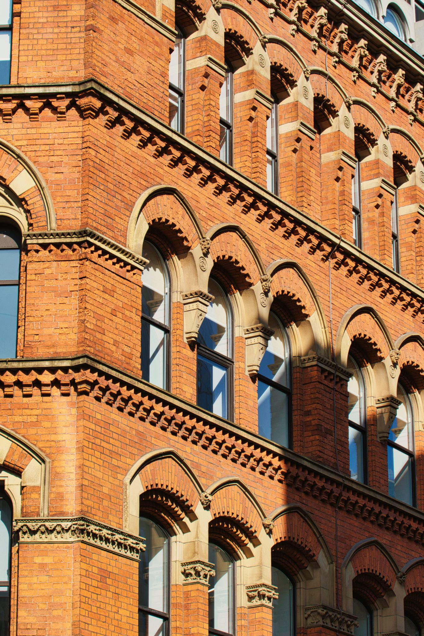 Brick Building Facade with Arched Windows in Manchester, UK.