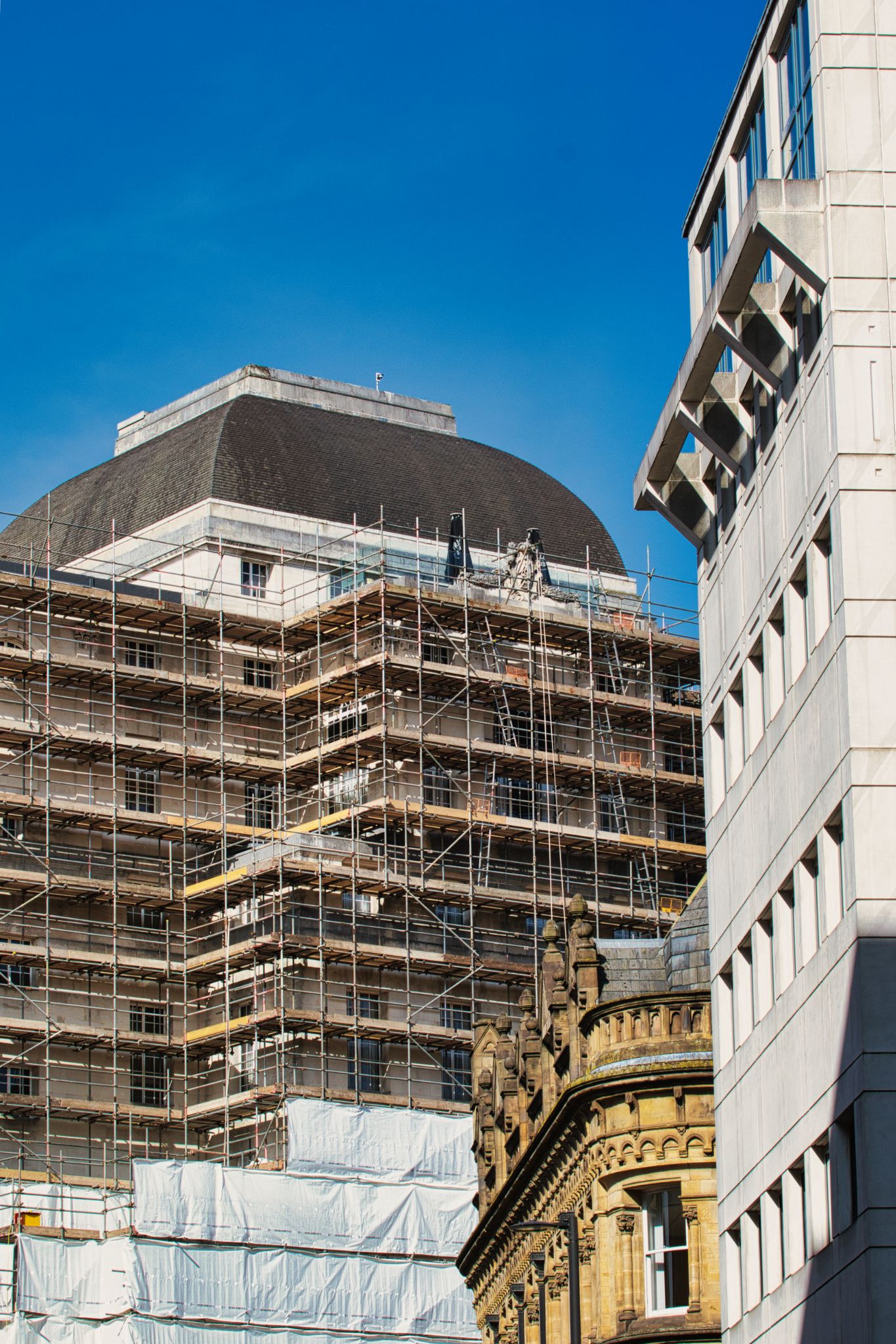 Building Under Scaffolding with Other Buildings and Blue Sky in Manchester, UK.