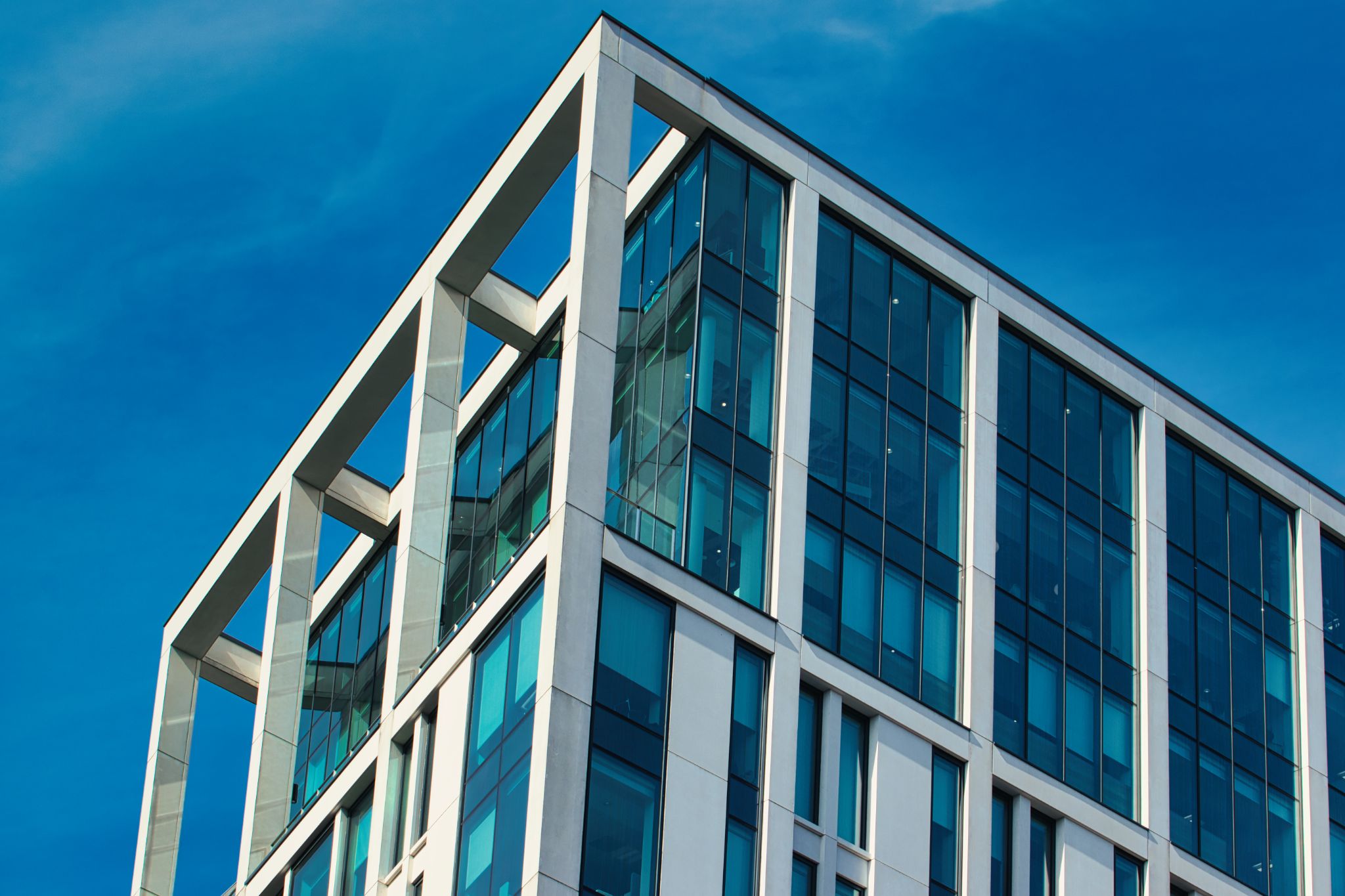 Modern Building with Glass Windows Against Blue Sky in Manchester, UK.
