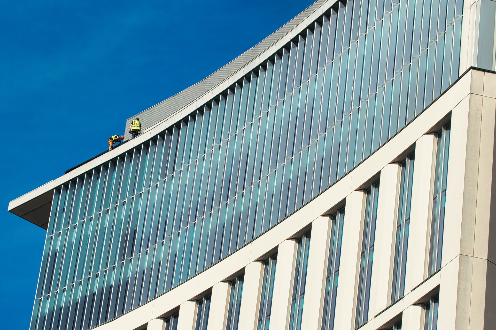 Modern Building with Glass Facade and Workers in Manchester, UK.