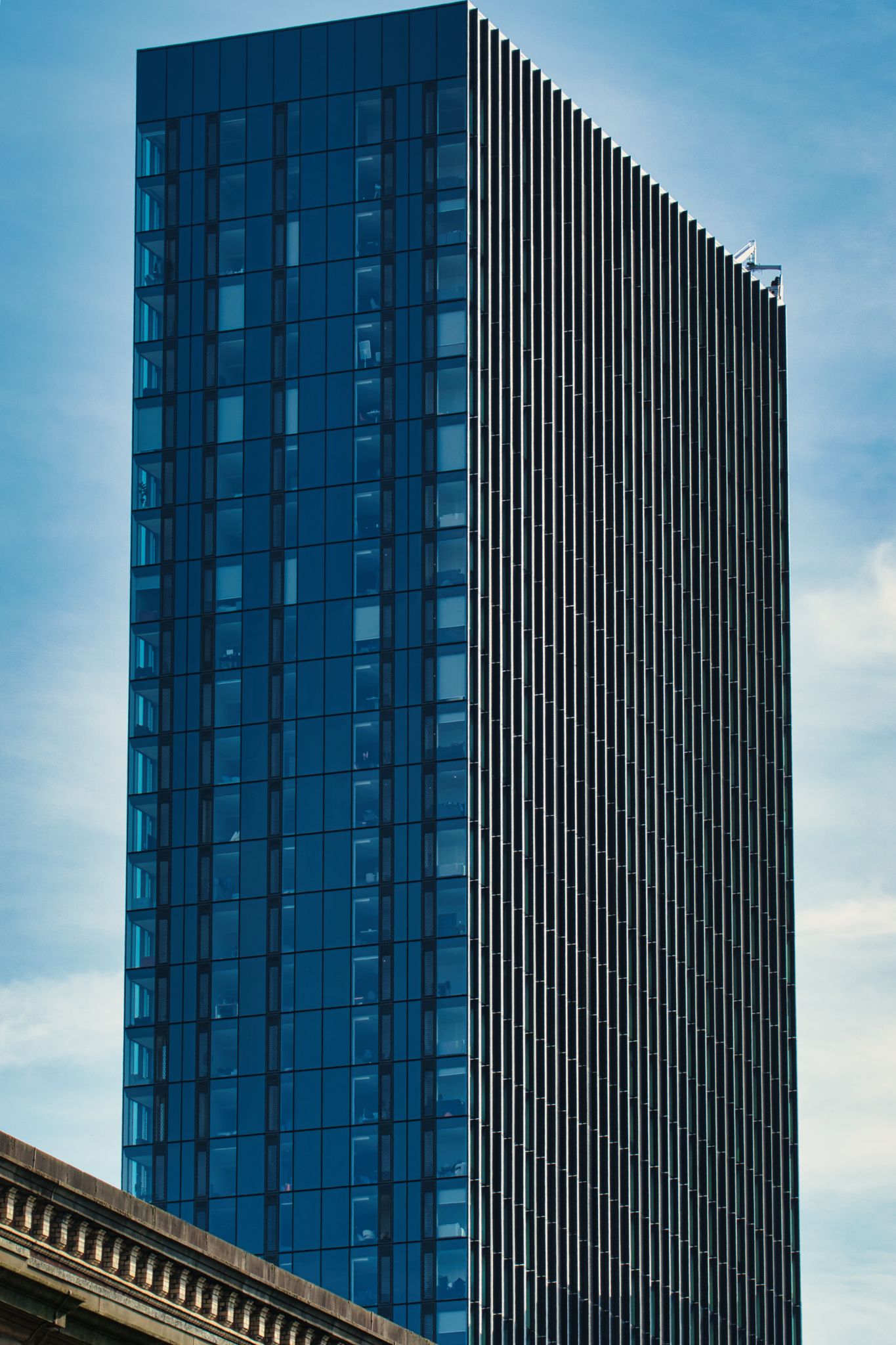 High-Rise Building with Glass Windows and Vertical Metal Slats in Manchester, UK.