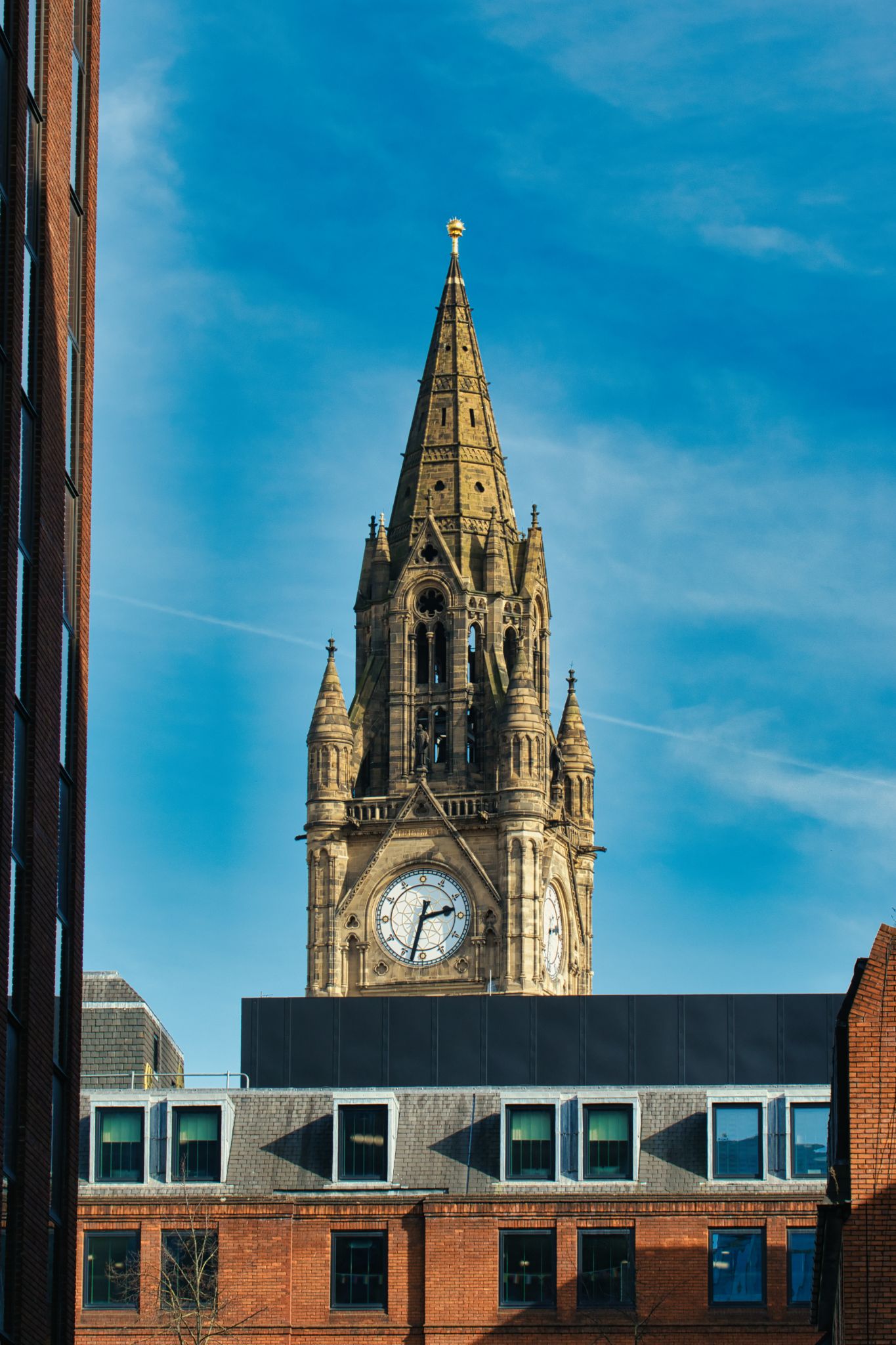 Clock Tower Spire Above City Buildings in Manchester, UK.