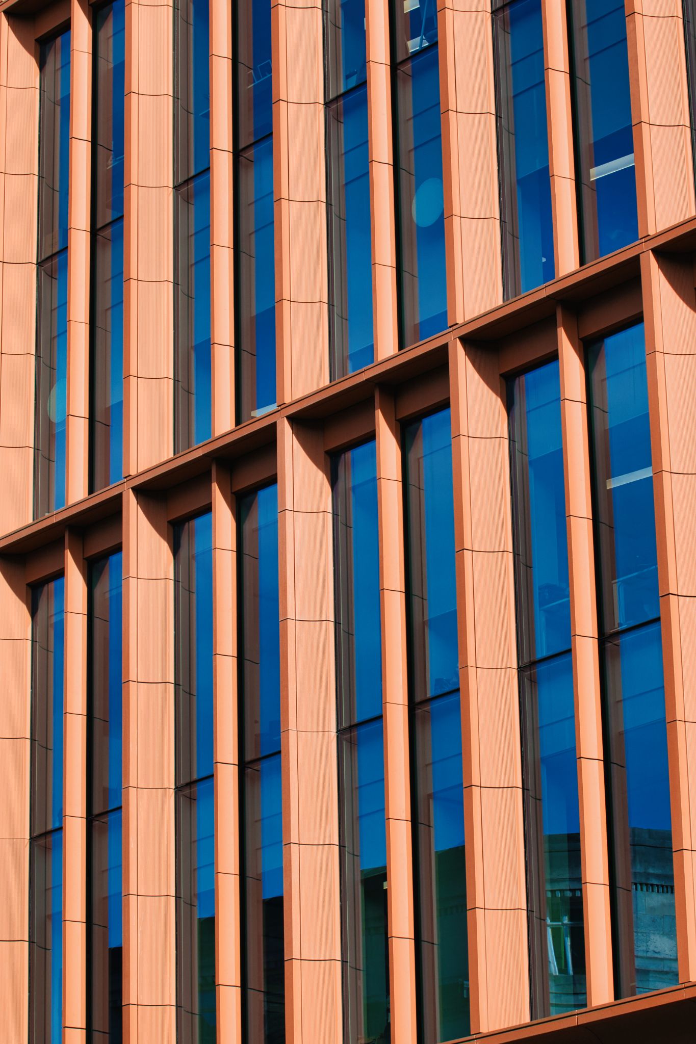 Building Facade with Peach Pillars and Blue Glass in Manchester, UK.