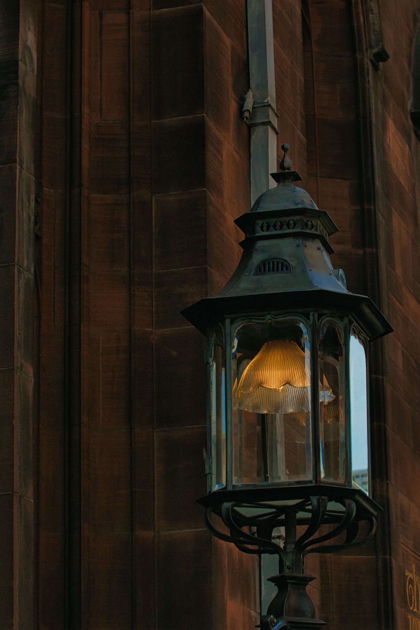 Illuminated Lantern on Stone Building Facade in Manchester, UK.