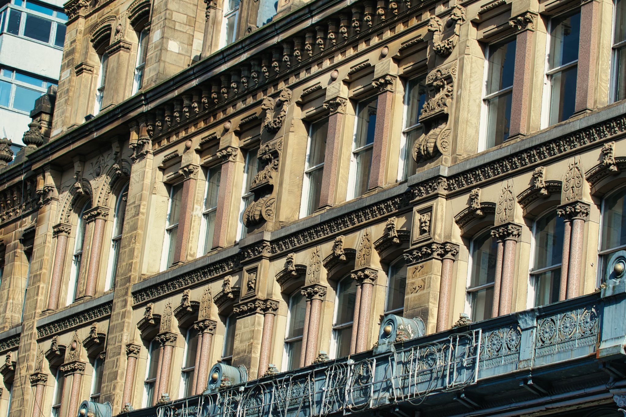 Building Facade with Windows, Ornate Details, and Balcony in Manchester, UK.