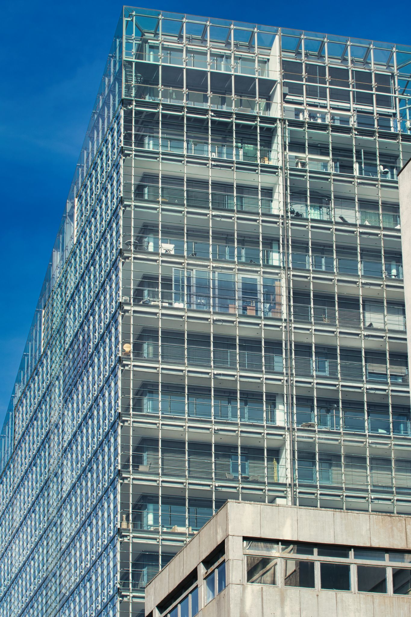 Modern Glass Building with Grid Façade Against Blue Sky in Manchester, UK.