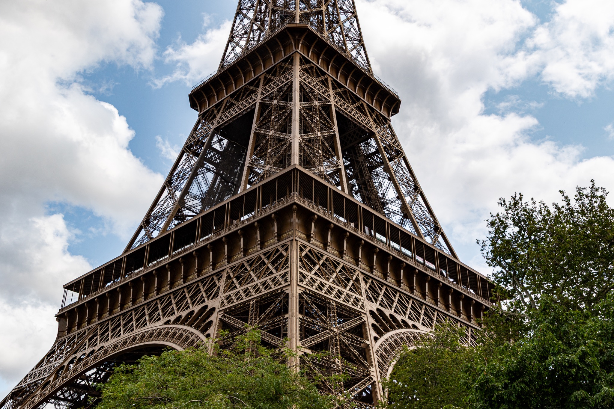 Eiffel Tower Structure with Trees and Cloudy Sky