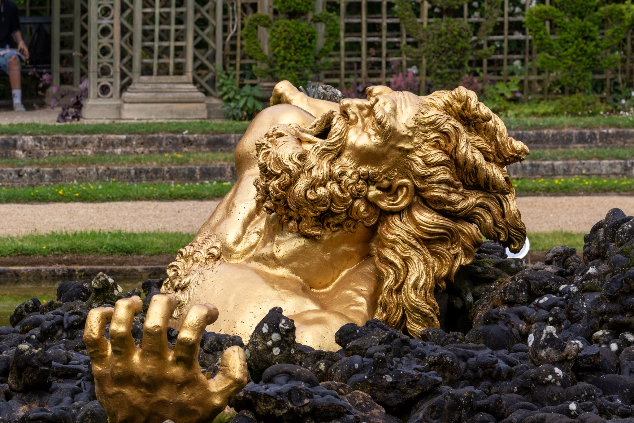 Golden Statue Lying in Rocks in Garden at Versailles Gardens, Paris.