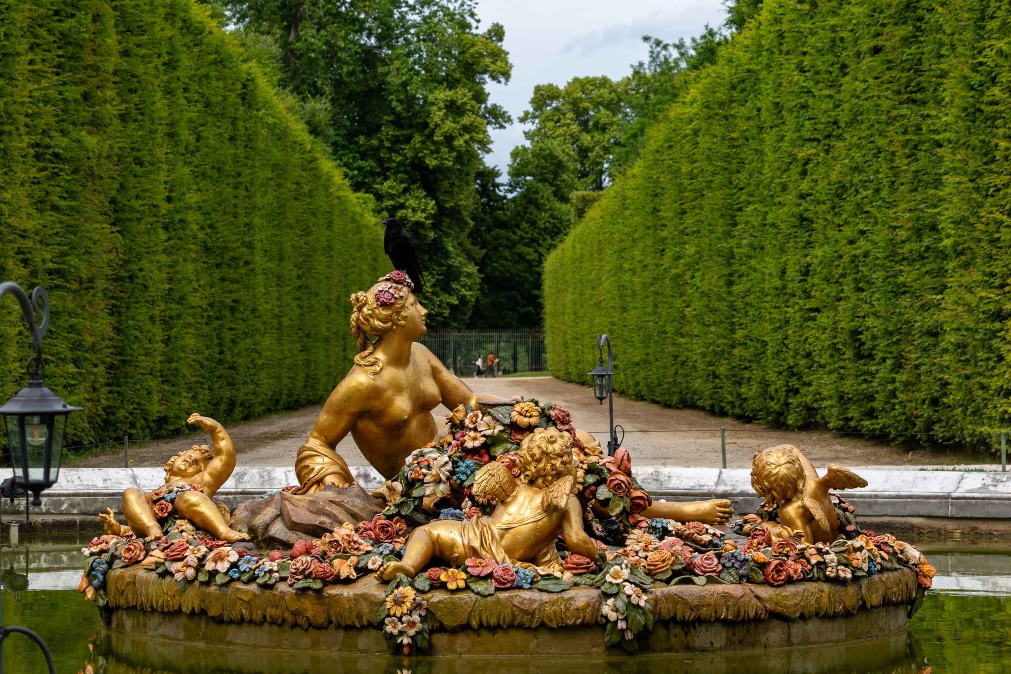 Fountain Statue with Woman, Cherubs, and Flowers in Garden at Versailles Gardens, Paris.