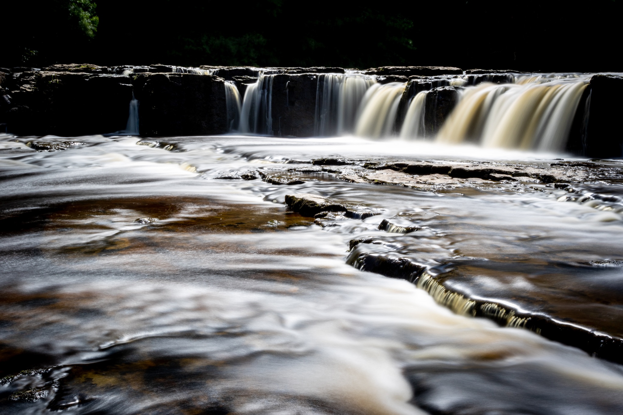 Silky smooth waterfall with a soft golden glow, captured in a serene natural setting.