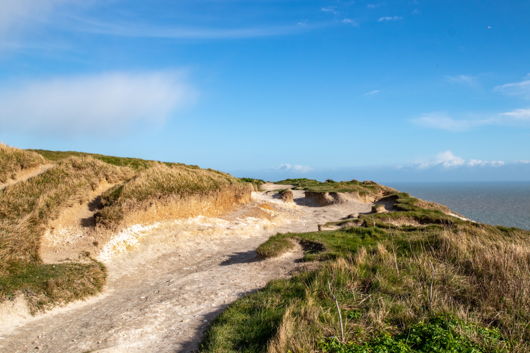 Coastal landscape with sandy dunes and a clear blue sky on a sunny day.