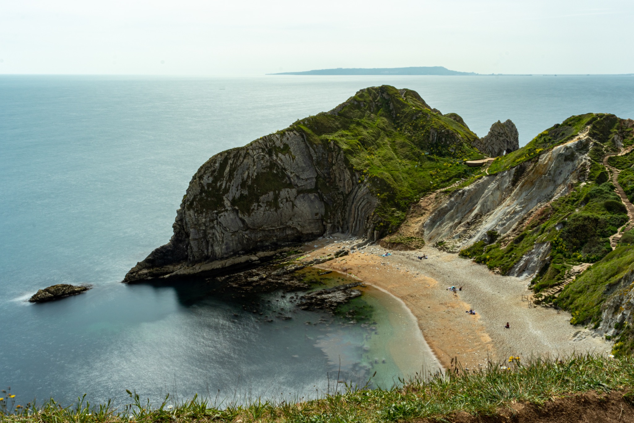 Scenic coastal landscape with cliffs and a secluded beach under a clear sky at Durdle Door, England.