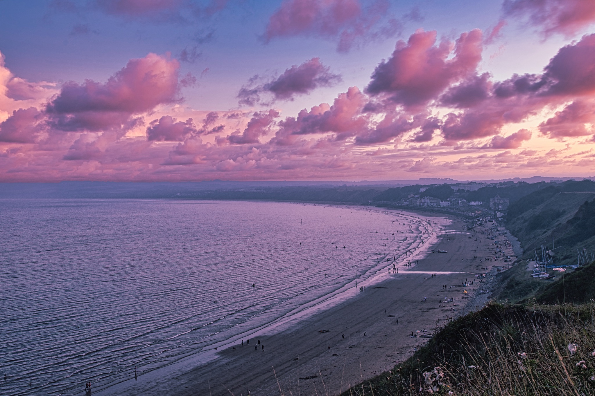 Scenic sunset view over a tranquil beach with pink clouds and a calm sea, showcasing the beauty of the coastline in Filey, England.