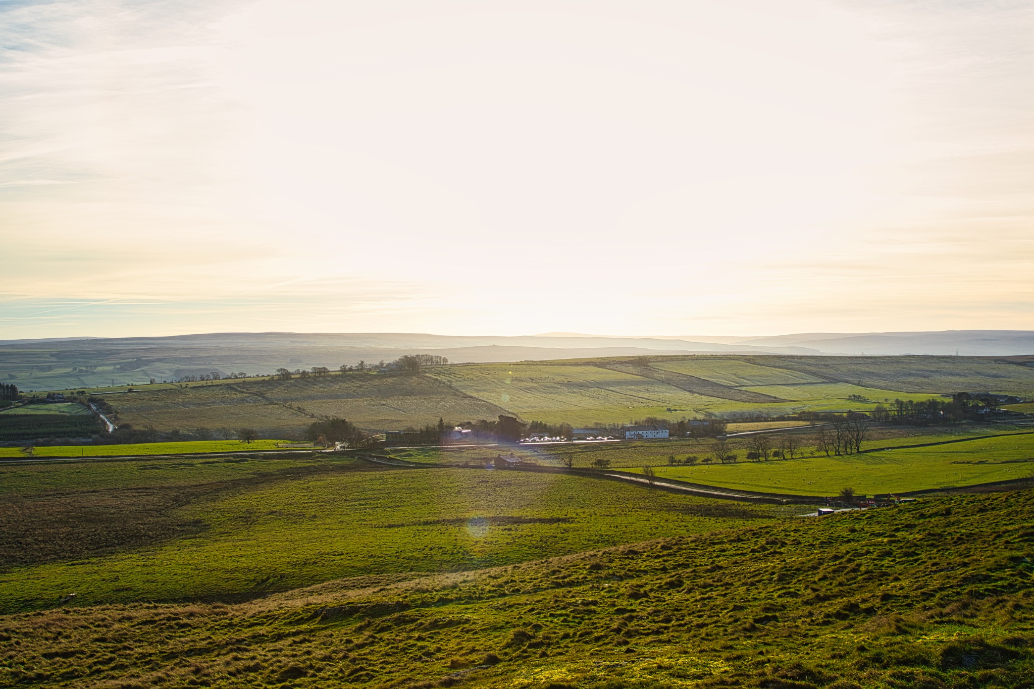 Serene countryside landscape at sunrise with rolling hills and a clear sky at Sycamore Gap, Northumberland, UK.
