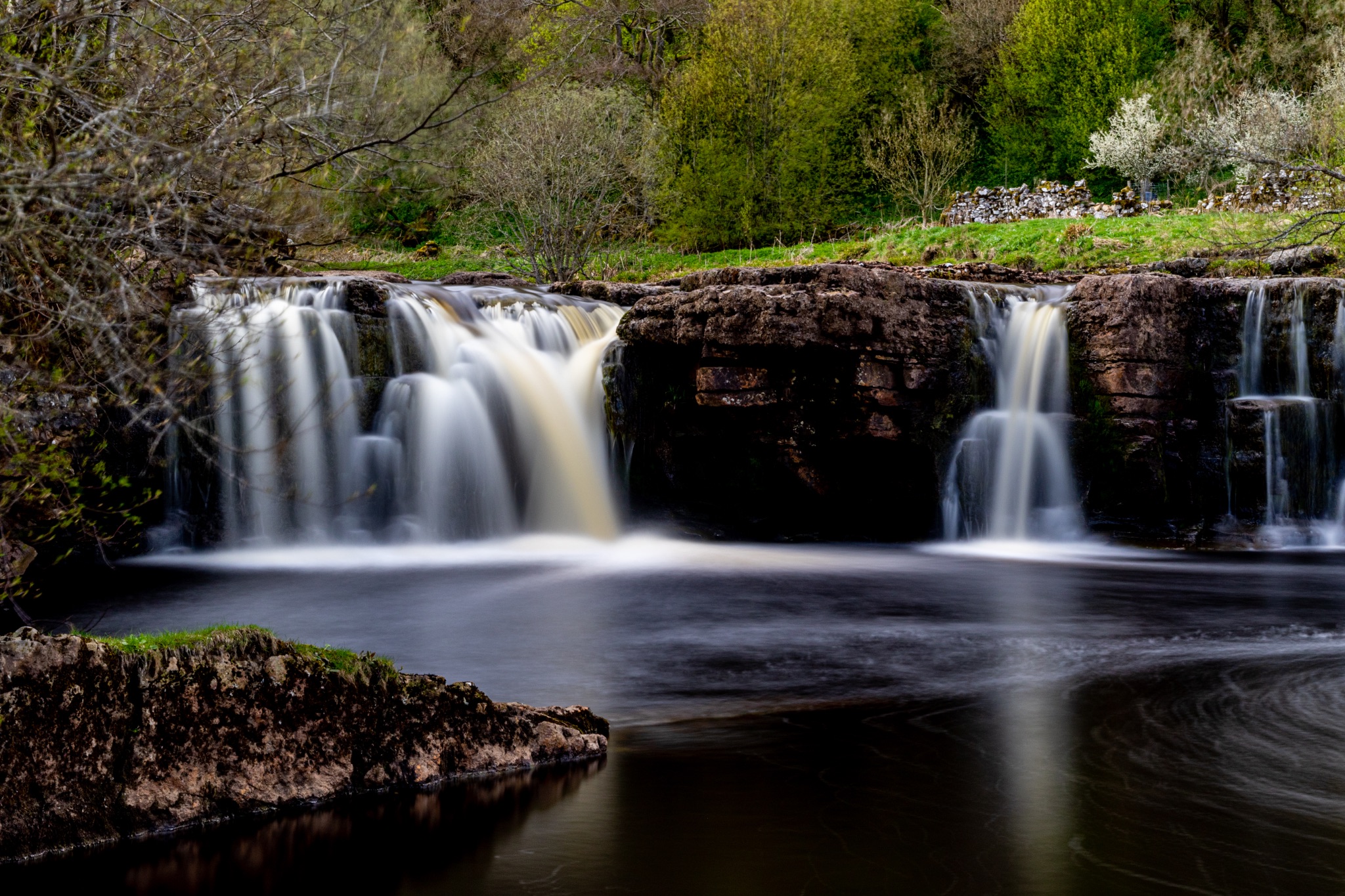 Serene waterfall with smooth flowing water in a lush green landscape, perfect for tranquil nature themes.