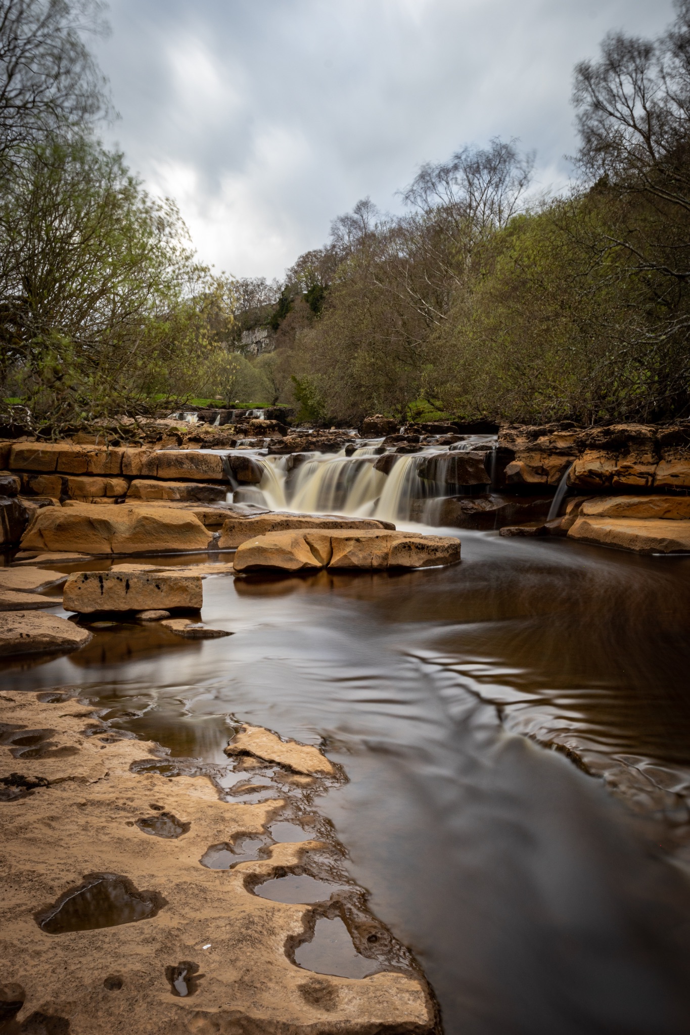 Serene waterfall cascading over rocks with lush greenery in the background, showcasing nature's tranquility.