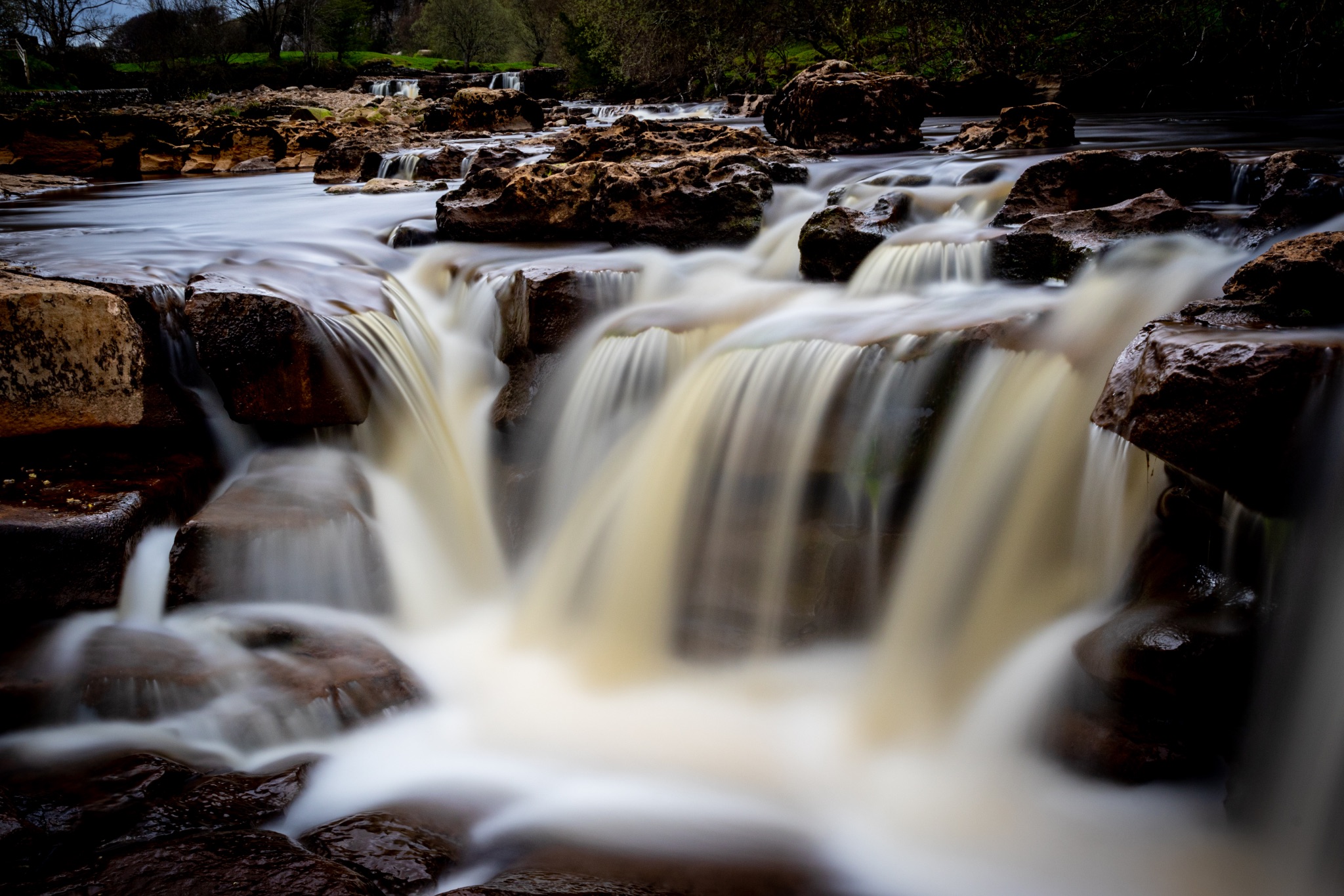 Serene waterfall cascading over rocks with lush greenery in the background, showcasing nature's tranquility.